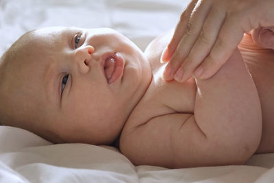 Mother giving massage to little child infant.  female hands massaging to newborn.  cream, body care