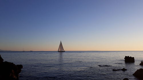 Sailboat in sea against clear sky