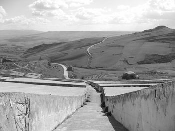 Footpath leading towards mountain against sky