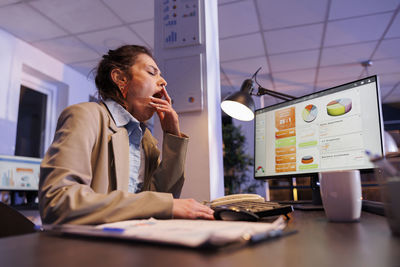 Side view of young businesswoman working at table