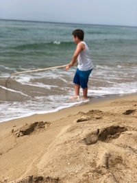 Full length of boy on beach against sea