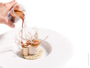 Close-up of hand holding ice cream over white background