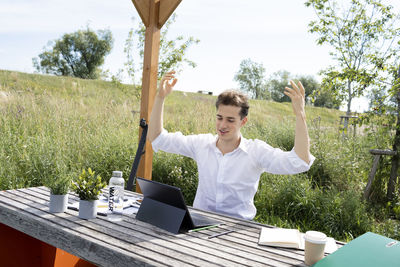 Portrait of young woman using mobile phone while sitting on table