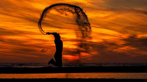 Silhouette woman standing on beach during sunset
