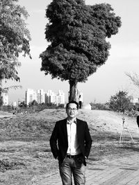 Portrait of mature man standing against tree and sky