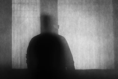 Portrait of silhouette man standing against wall