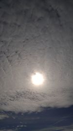 Low angle view of sun shining through clouds