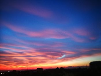 Silhouette city against sky during sunset