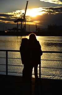 Silhouette couple by sea against sky during sunset