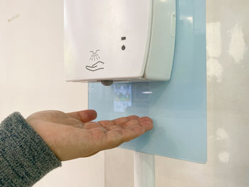 Close-up of hand holding paper against wall