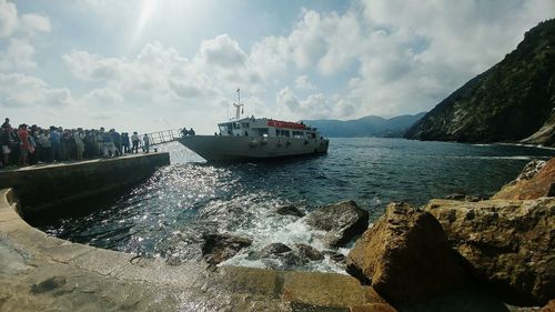 People waiting for ferry at harbor against sky