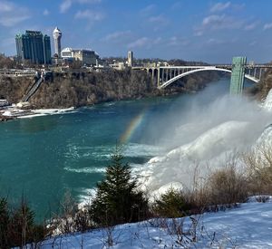 Bridge over river during winter at niagara falls, ny under a blue sky with a rainbow 