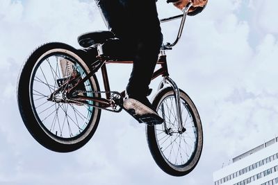Low section of man riding bicycle against sky