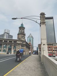 People on road by buildings in city