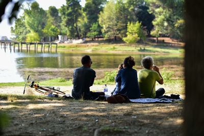 People sitting on lake against trees