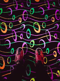 Low section of people standing on illuminated multi colored light