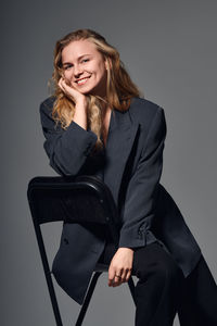 Portrait of young woman standing against gray background