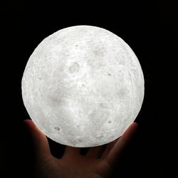 Close-up of hand holding moon over black background