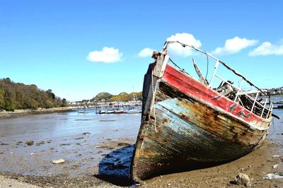 Abandoned boat at beach against sky