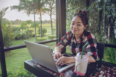 Young woman looking through mobile phone while sitting on table