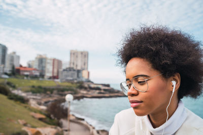 Portrait of beautiful young woman in city against sky