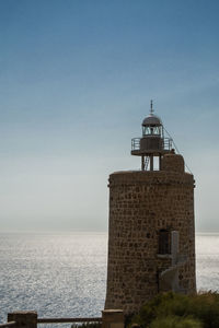 Lighthouse by sea against sky