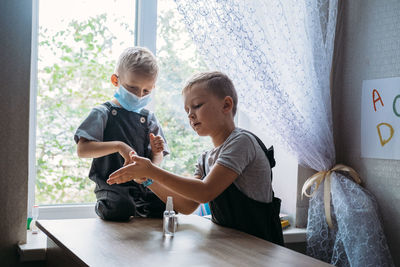 Back to school safety. schoolkids wearing masks and using antiseptic in classroom at school