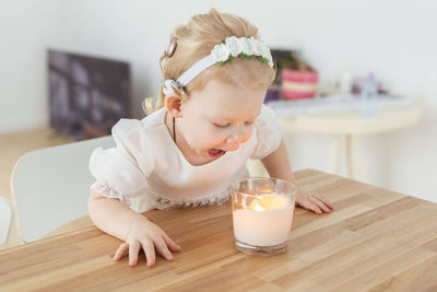 Cute deaf girl looking at candle on table