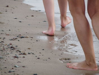 Low section of person standing on wet sand