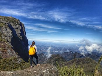 Woman standing on rock against sky