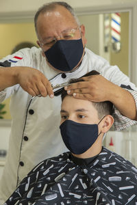 View of barber cutting hair of boy at barber shop
