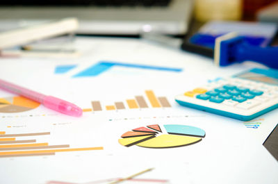 Close-up of graph papers and calculator on desk