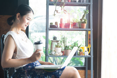 Young woman sitting by window at home