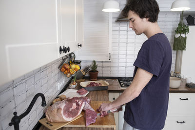 Real men cutting fresh raw meat on board in white kitchen. preparing pork meat, cooking.