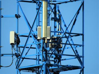 Low angle view of electricity pylon against clear blue sky