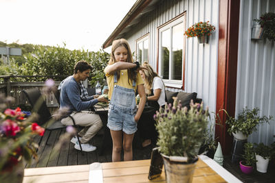 Daughter with hand in pocket against parents in balcony