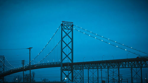 Low angle view of suspension bridge against blue sky ambassador bridge