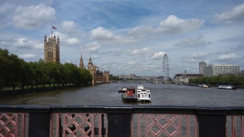 View of city at waterfront against cloudy sky