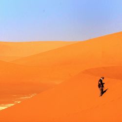 Man riding motorcycle on desert against clear sky