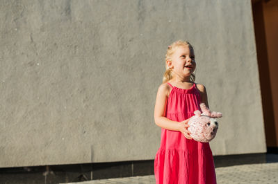 Portrait of young woman standing against wall