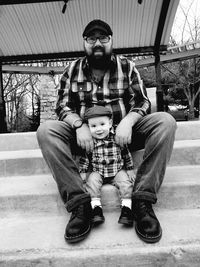 Full length of father with son sitting outdoors