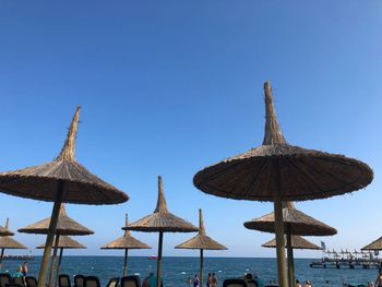 Traditional windmill on beach against clear blue sky