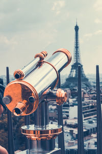 Close-up of telescope against eiffel tower in city