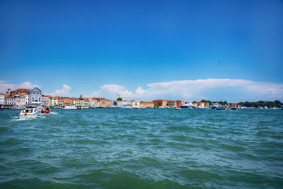 View of buildings at waterfront against blue sky