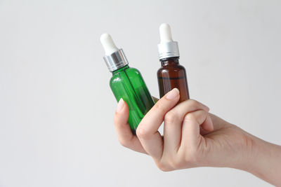 Cropped hand holding bottle against white background