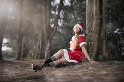 Woman sitting on tree trunk in forest