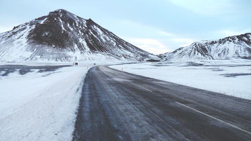 Pathway amidst snowy field leading towards mountains