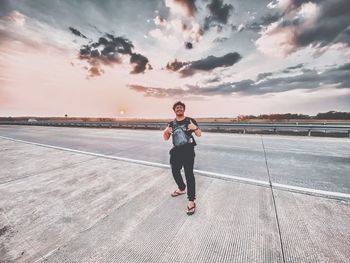 Full length of man standing on road against sky during sunset