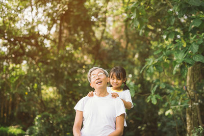 Grandfather with granddaughter against trees