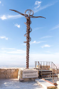 Metal sculpture by sea against sky